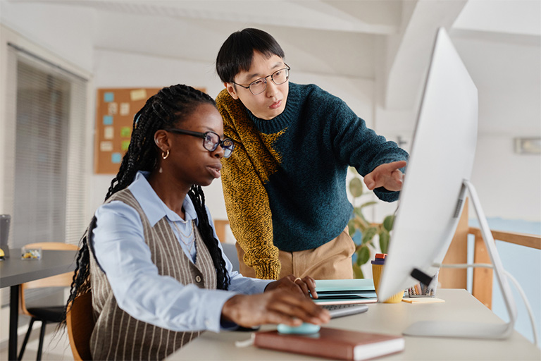 two individuals taking in front of a computer