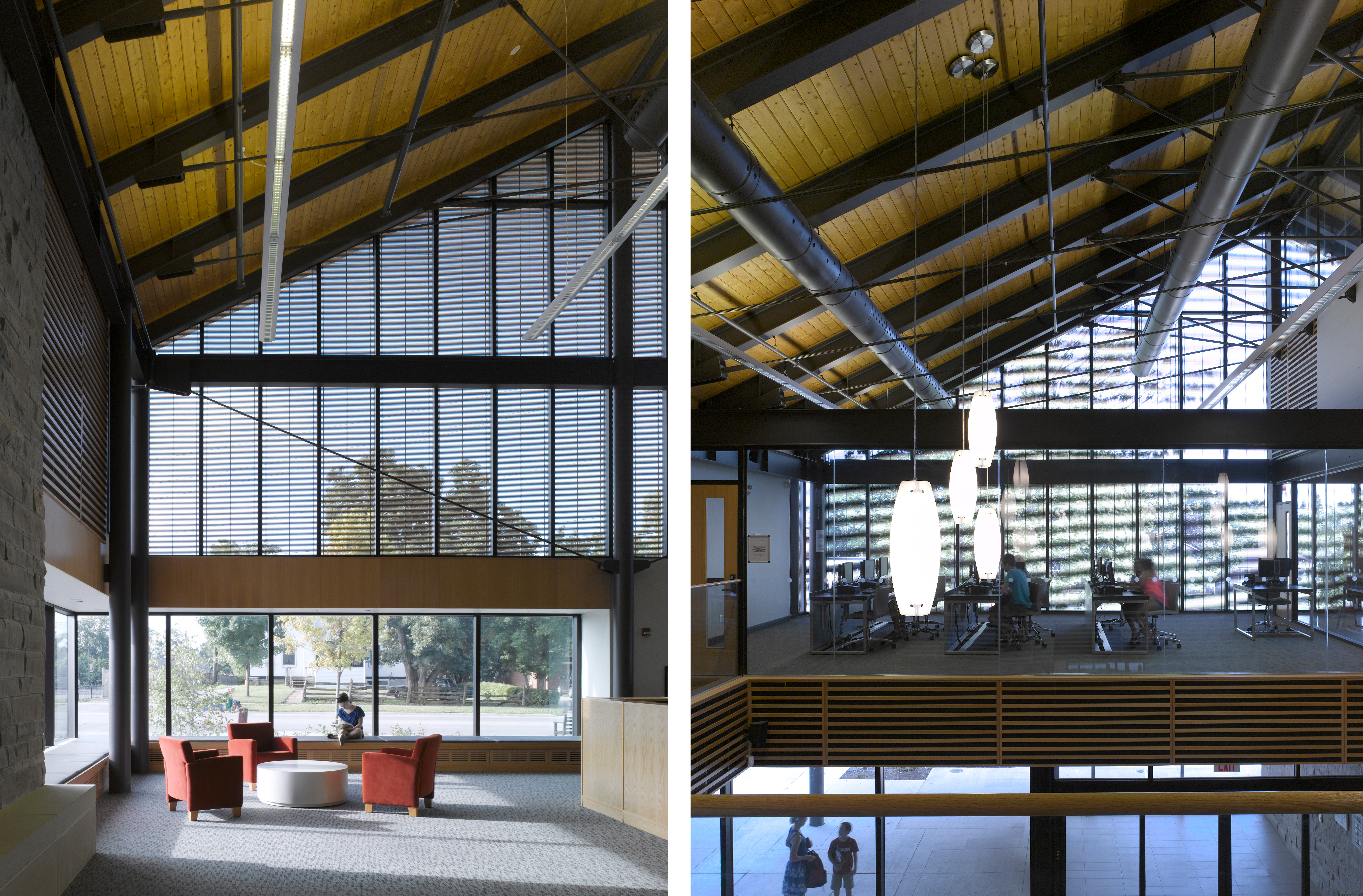Left: Lounge chairs and a person reading a book in front of large shaded windows in a double height space. Right: Computer workstations in the distance under a sloped wood and steel ceiling.
