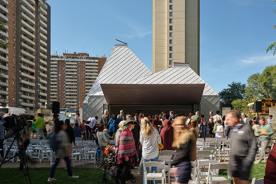 The Belle" opens its doors to the stage during an event with a diverse crowd and white chairs. 